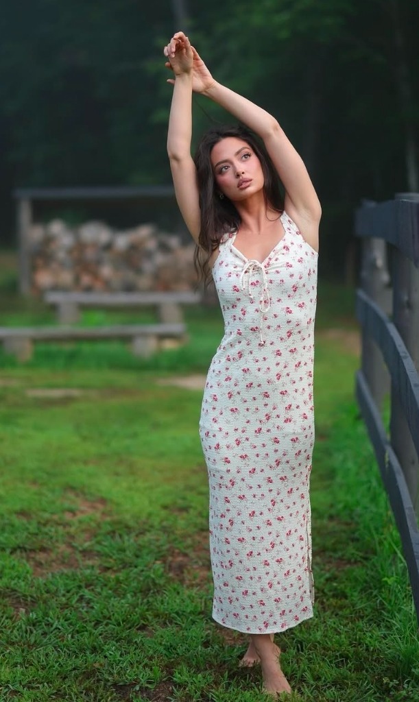 Mercy portrait standing in a meadow wearing a floral dress